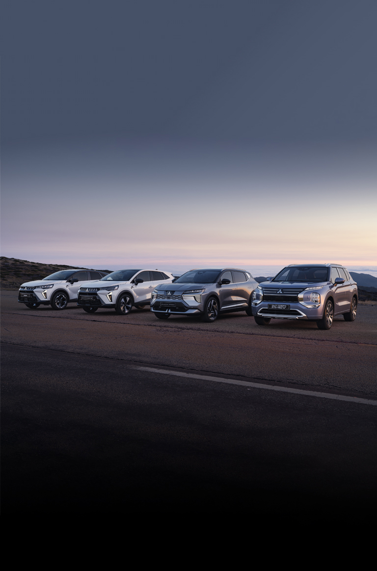 Die Mitsubishi Modell-Range Die Mitsubishi ASX, Grandis, Eclipse Cross und Outlander stehen in der Dämmerung am Straßenrand.