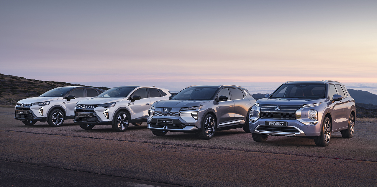 Startseite: Range Vier Mitsubishi Modelle, darunter der Grandis, ASX, Eclipse Cross und Outlander, stehen nebeneinander auf einem offenen Platz vor weiter Landschaft bei Sonnenuntergang.