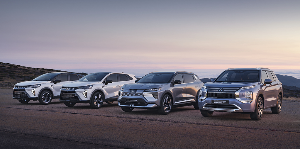 Startseite: Range Vier Mitsubishi Modelle, darunter der Grandis, ASX, Eclipse Cross und Outlander, stehen nebeneinander auf einem offenen Platz vor weiter Landschaft bei Sonnenuntergang.