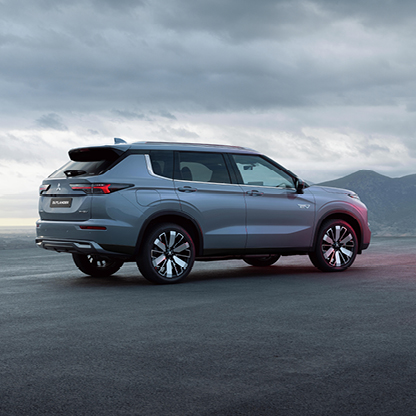 Mitsubishi Outlander Select Heckansicht – dynamisches Design Silberner Mitsubishi Outlander Select in der Heckansicht vor bewölktem Himmel und Berglandschaft