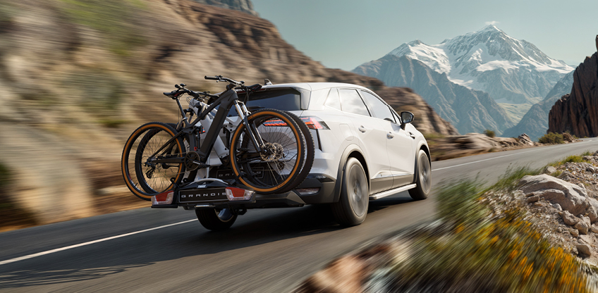 Grandis Zubehör Grandis mit Fahrradheckträger fährt einen Bergpass hinauf.