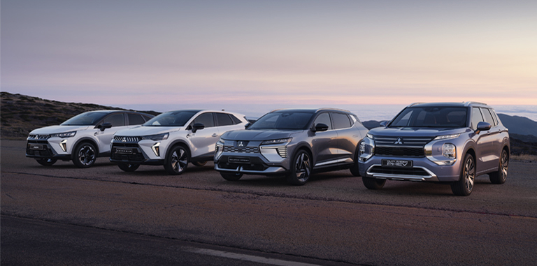Die Mitsubishi Modell-Range Die Mitsubishi ASX, Grandis, Eclipse Cross und Outlander stehen in der Dämmerung am Straßenrand.
